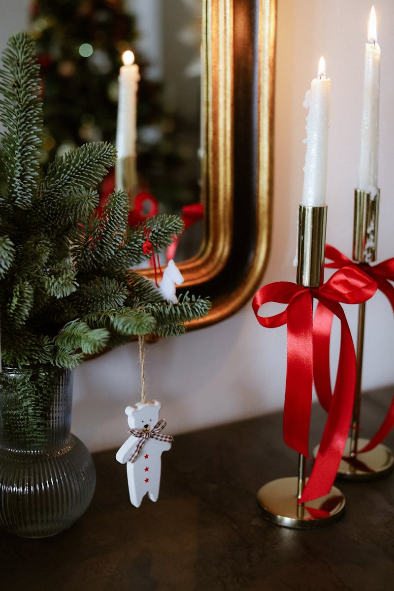 Elegant holiday decor with candles, red ribbons, and pine branches.
